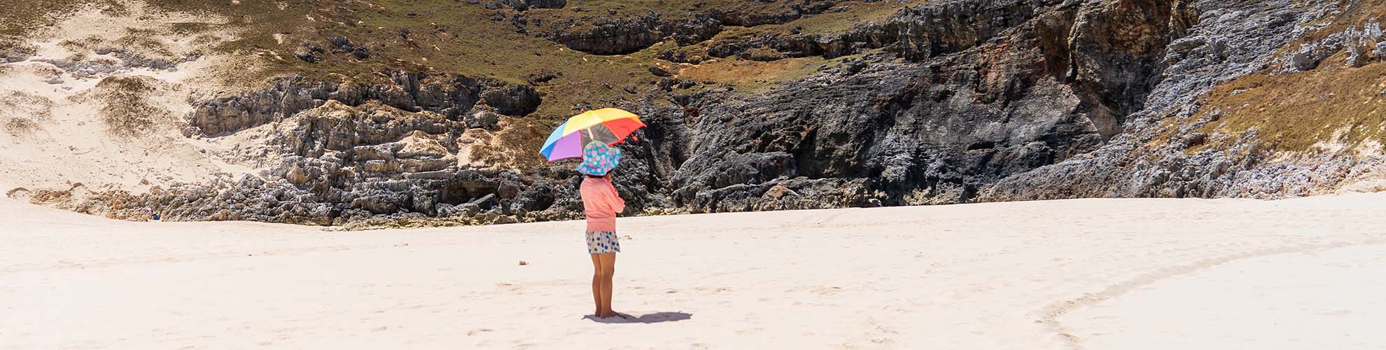 砂浜で日傘をさす子供